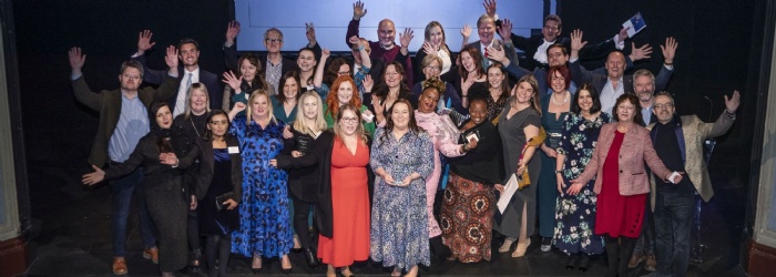 A group of people on stage with their arms in the air, celebrating the Northamptonshire Community Foundation Annual Awards 2022